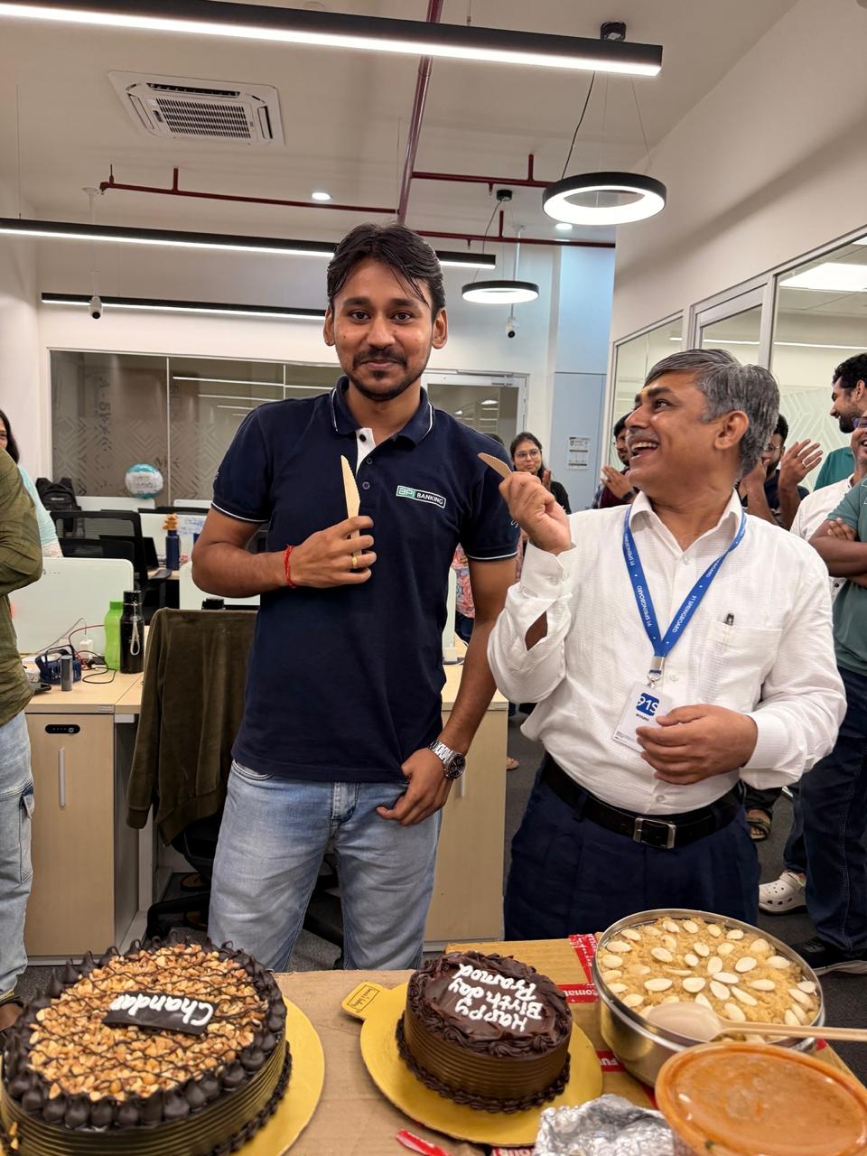 Two colleagues laughing at an office cake cutting