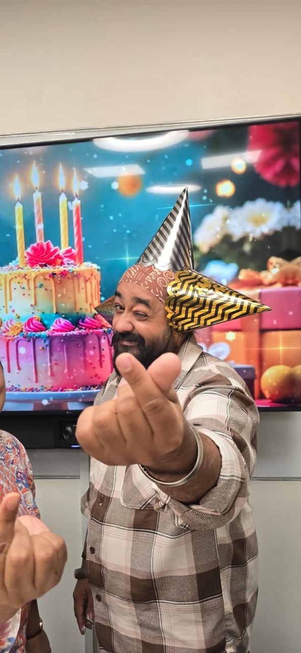 A colleague in a party hat winking and making a finger heart
